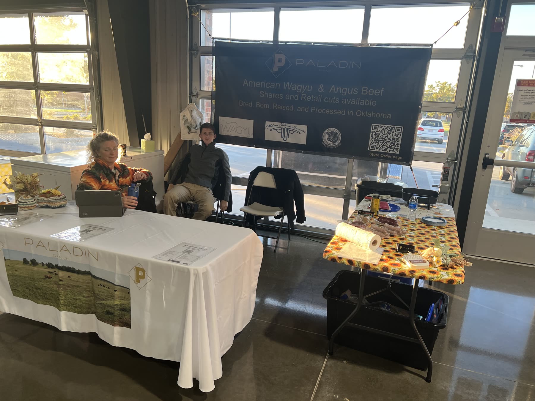 The Paladin Ranch farmers market booth with banner, samples, and the family behind the table