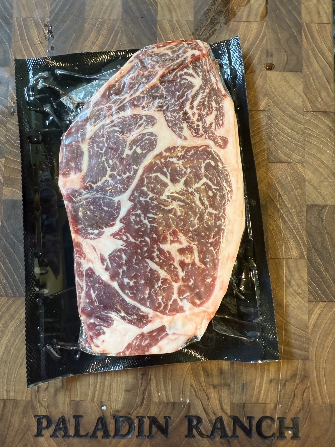 American Wagyu ribeye, vacuum-sealed on the Paladin Ranch butcher block, showing dense marbling