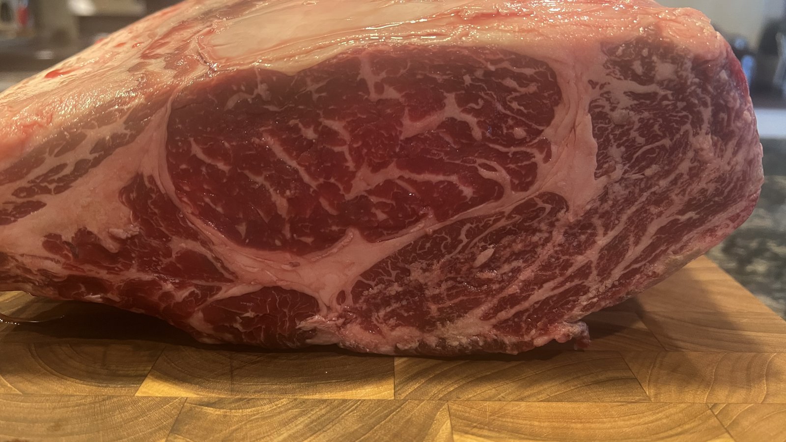 Standing Wagyu rib roast with dense marbling on the butcher block