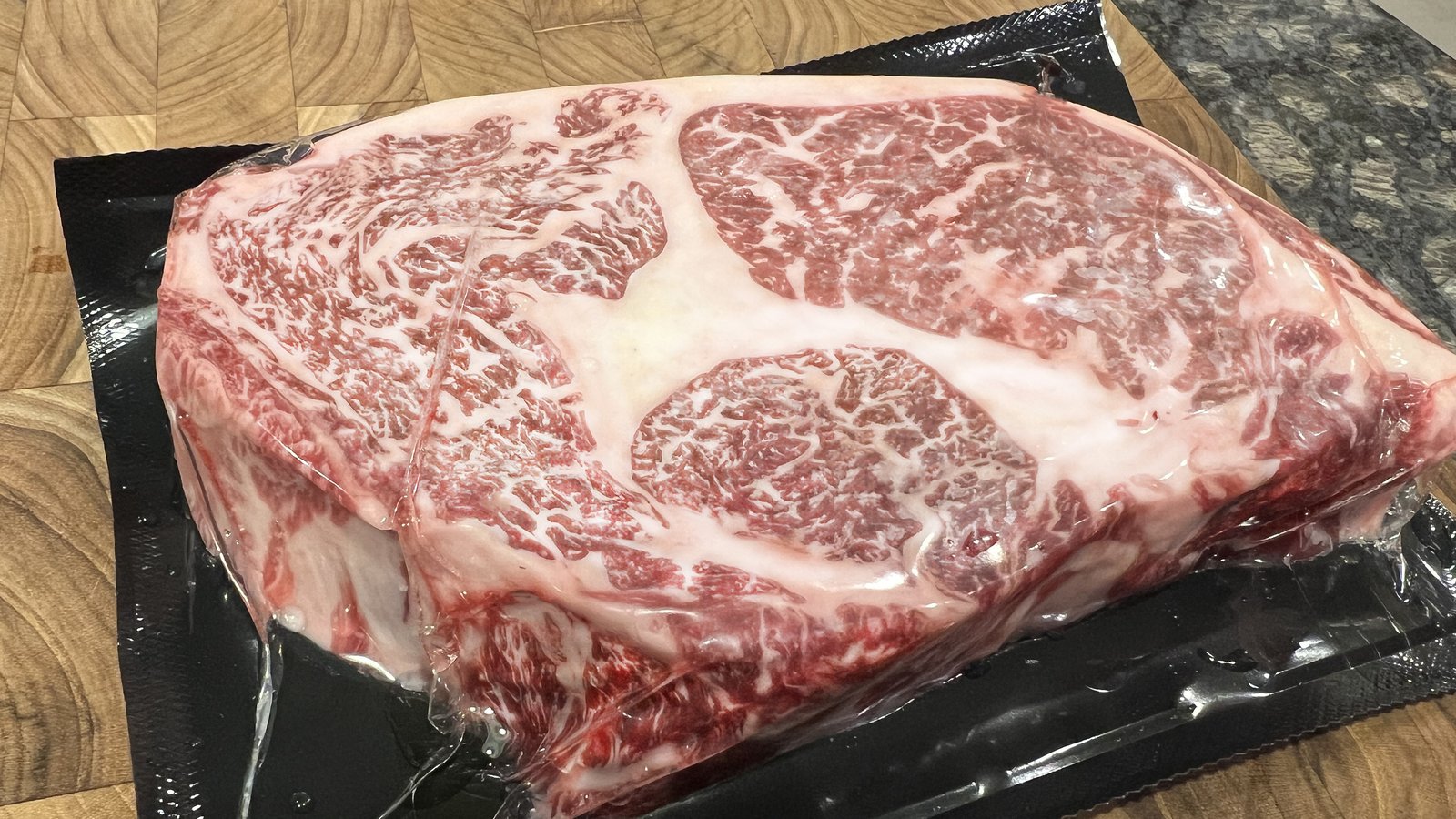 Wagyu ribeye steak vacuum-sealed, dense marbling through the seal