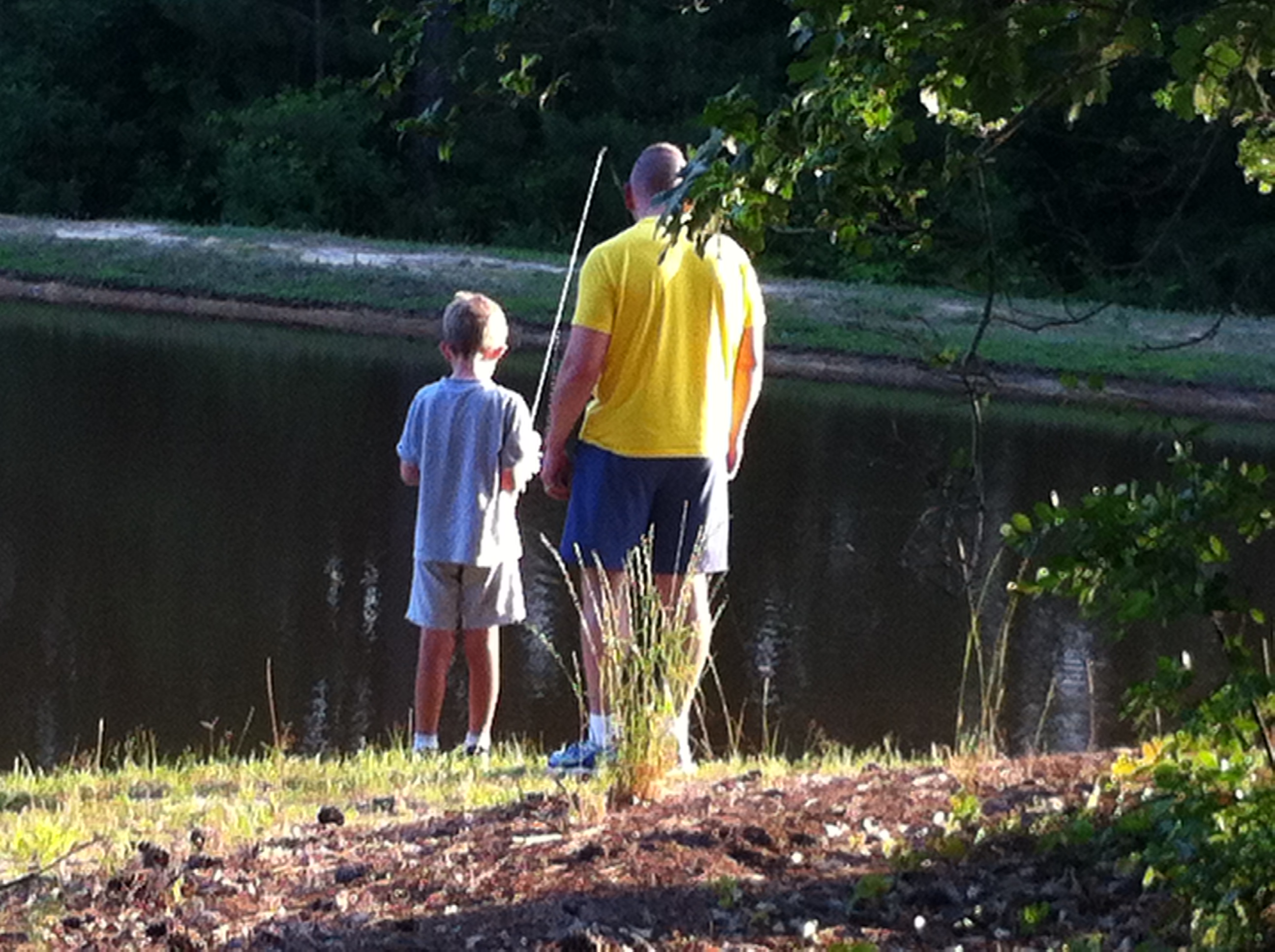 Father and son fishing together at a pond, 2014