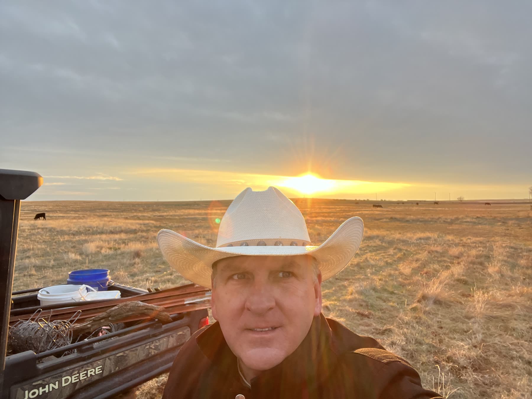 John Spivey at golden hour on the ranch, cattle grazing behind him
